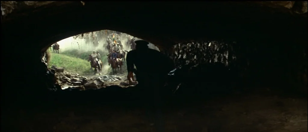 Butch Cassidy and the Sundance Kid (1969) movie still: wide — A dark, arched cave interior frames an outdoor landscape filled with hazy dust. A…