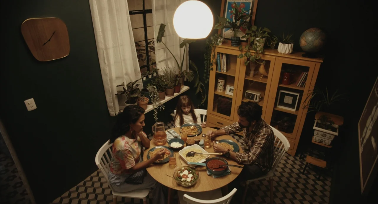 The Diary (1999) movie still: wide — A dining room features deep green walls with a yellow hutch and tile floor. A man, woman, and child sit at a…