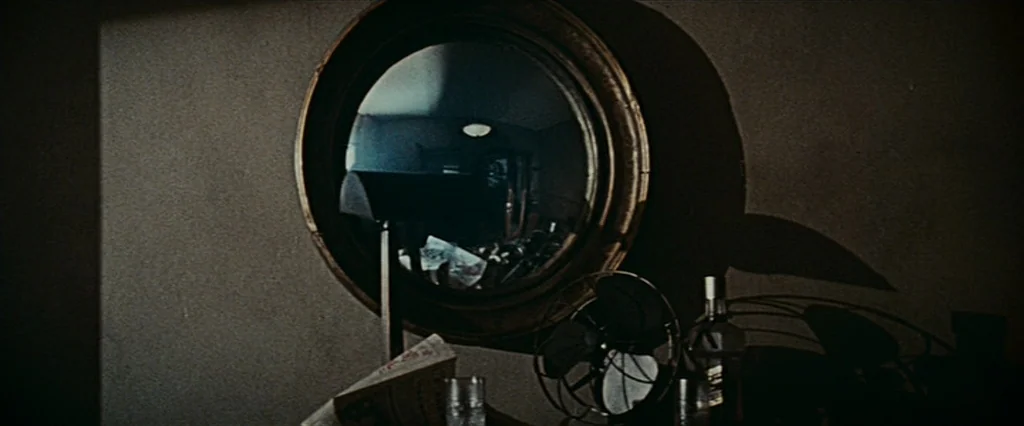 Blade Runner (1982) movie still: medium — A dark study contains a round mirror reflecting the opposite side of the room. Objects including a small…