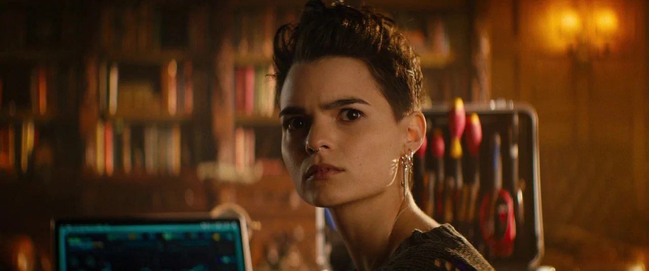 Deadpool 2 (2018) movie still: closeup — A dimly lit room features a bookshelf in the background and a tool kit beside. A woman looks at the camera…