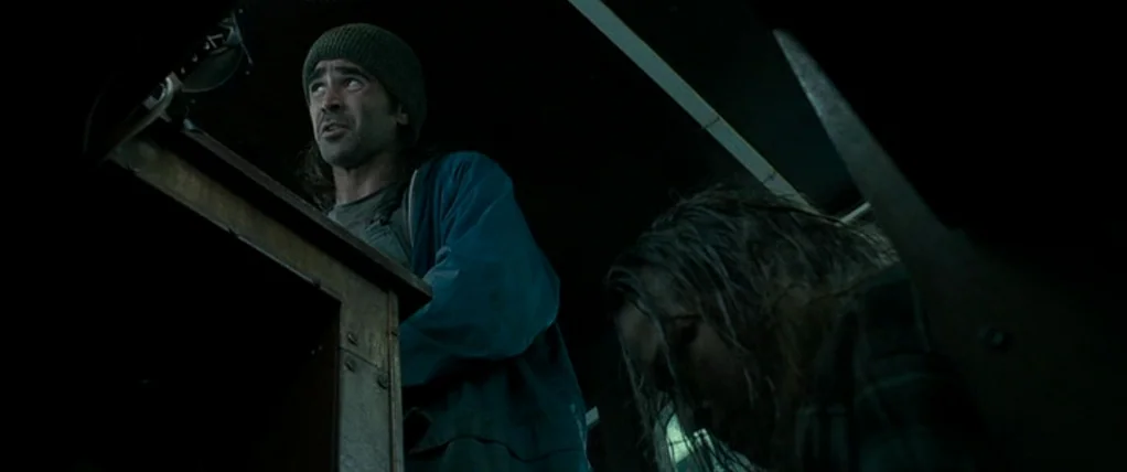 Ondine (2009) movie still: medium — A dark, cramped interior of a vehicle with wooden paneling and low visibility. A man looks up toward the ceiling…