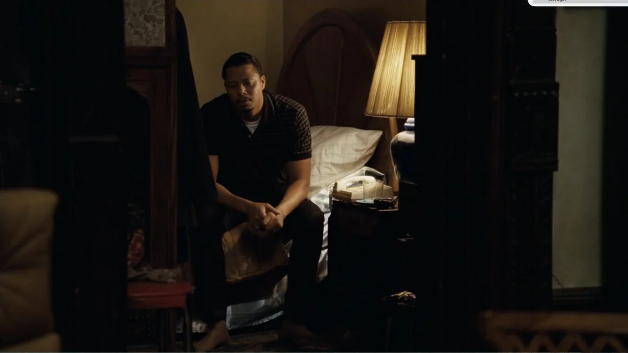 Fighting (2009) movie still: medium — A small room containing a bed and a wooden side table with a lamp. A man sits on the side of the bed while…