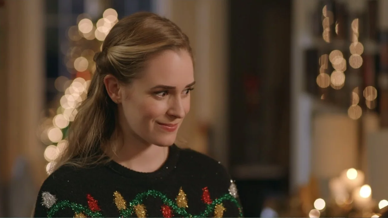 Loving Christmas (2022) movie still: medium — A woman stands indoors in a home decorated with festive holiday fairy lights. She is wearing a…
