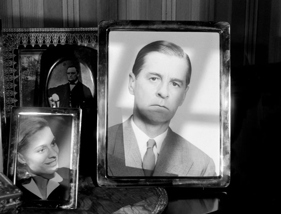 Wild Strawberries (1957) movie still: closeup — Three framed portraits sit clustered together on a dark surface in an interior room. A prominent…