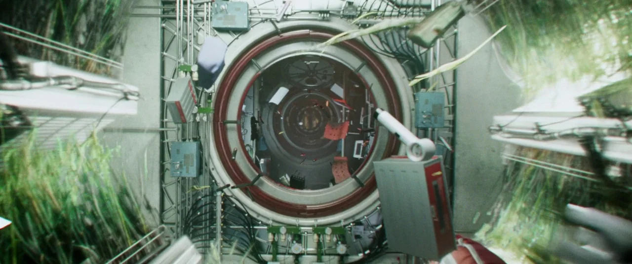 Gravity (2013) movie still: establishing — A high-tech spacecraft corridor features a large circular airlock door at its center. Various electronic…