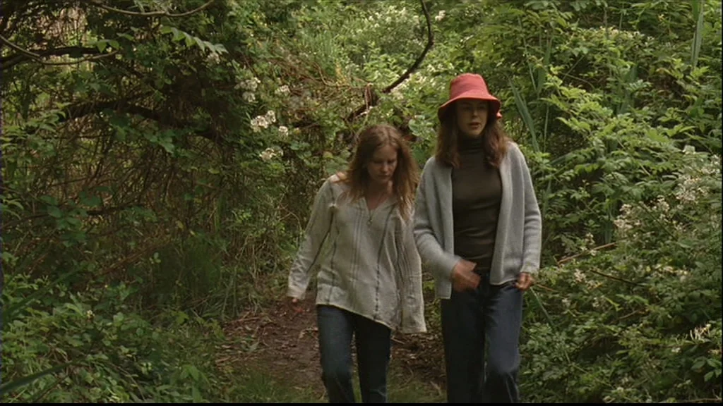 Margot At The Wedding (2007) movie still: fullbody — A dense overgrown trail is flanked by thick greenery and white flowering bushes. Two young…