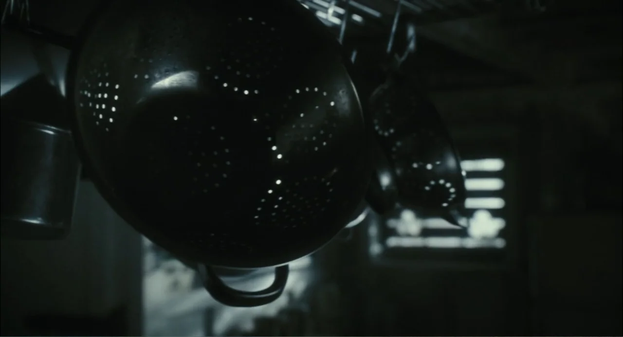 El hijo del diablo (1966) movie still: closeup — A metal colander hangs in a darkened interior with a faint light source behind. The perforated…