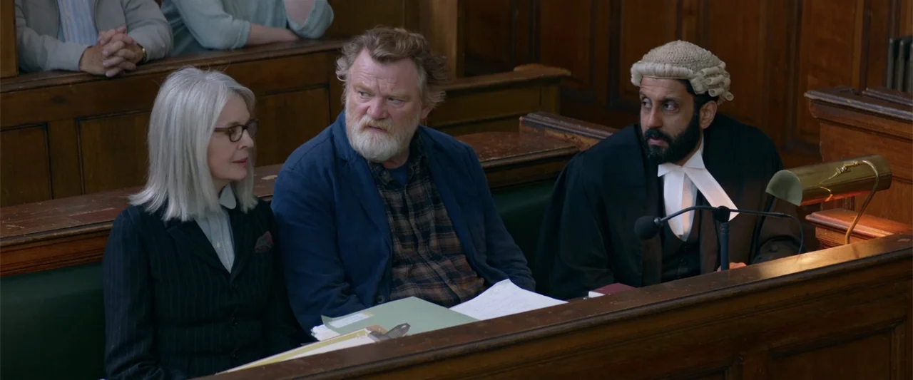 Hampstead (2017) movie still: medium — A wood-paneled courtroom features three people seated behind a polished desk in the foreground. They observe…