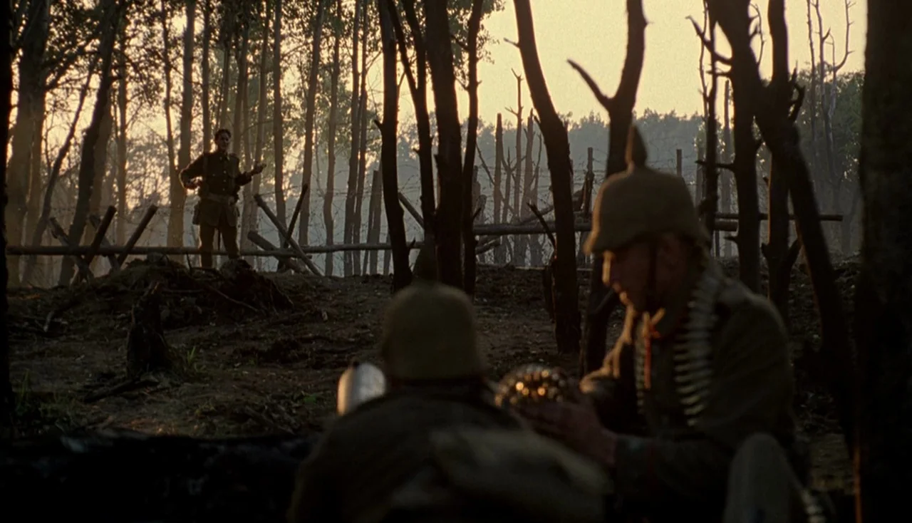 Legends of the Fall (1994) movie still: wide — A wooded area featuring barbed wire entanglements under a low golden sun. Two German soldiers prepare…