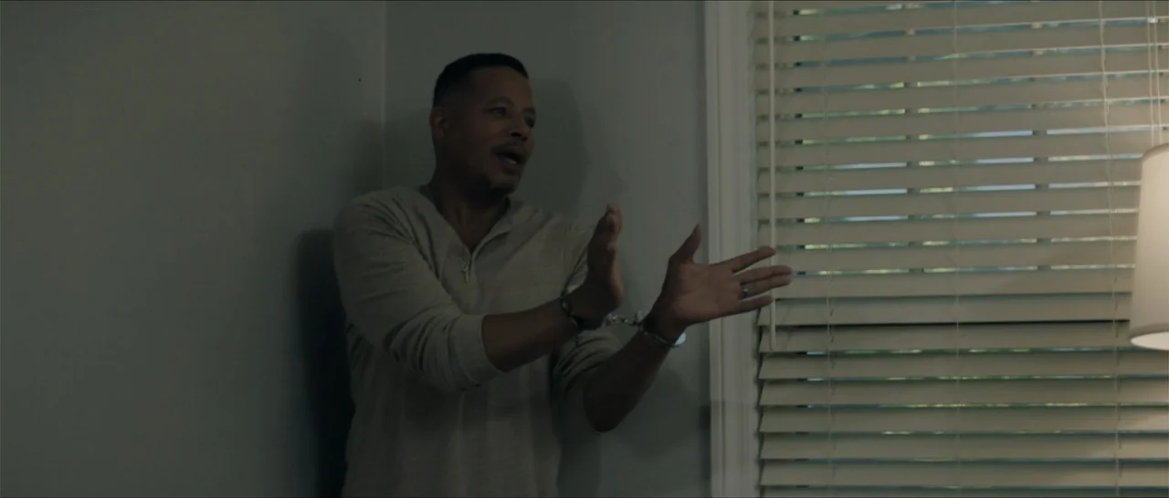 Crescent City (2024) movie still: medium — An interior room features a plain wall and a window covered by horizontal blinds. A man in a cream henley…