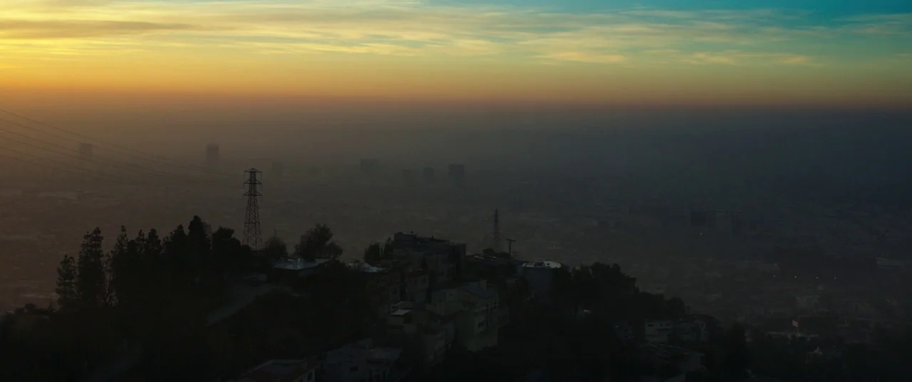 Nightcrawler (2014) movie still: establishing — A hazy urban valley stretches out beneath a hillside populated with dark silhouettes of buildings.…