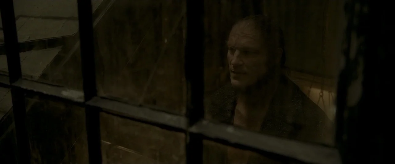 Harry Potter & The Half Blood Prince (2009) movie still: medium — A dark, cramped room featuring a heavy metal-framed window with visible grime. A…