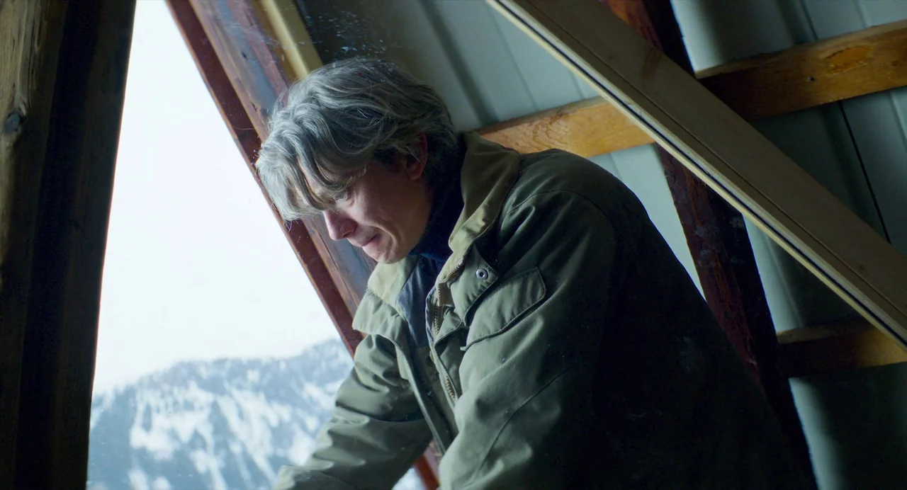 Anatomy of a Fall (2023) movie still: medium — An attic space with exposed wooden beams and a slanted window overlooking snowy mountains. A…