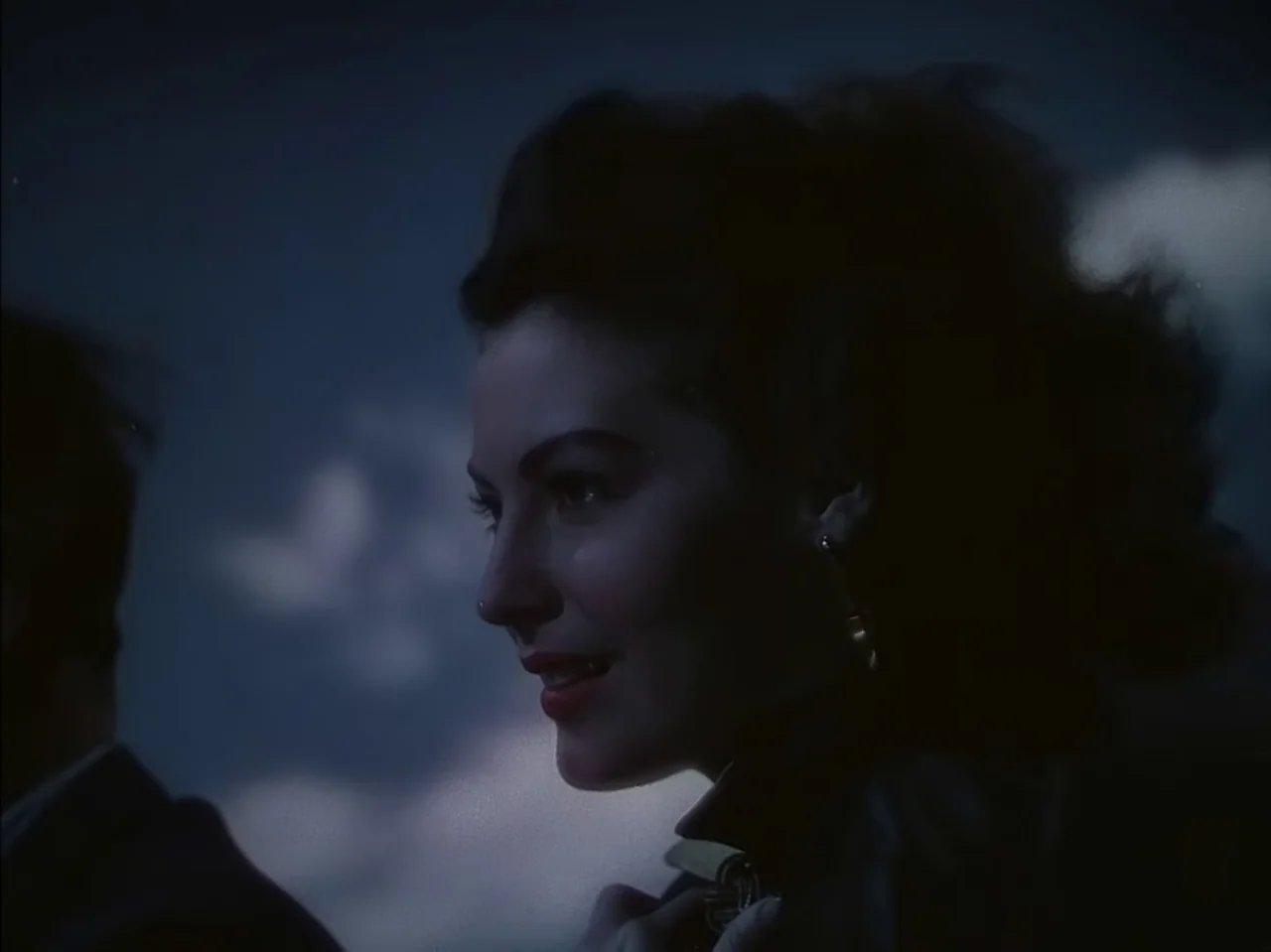 Pandora and the Flying Dutchman (1951) movie still: closeup — A dark outdoor space features a person visible against a night sky background. The…