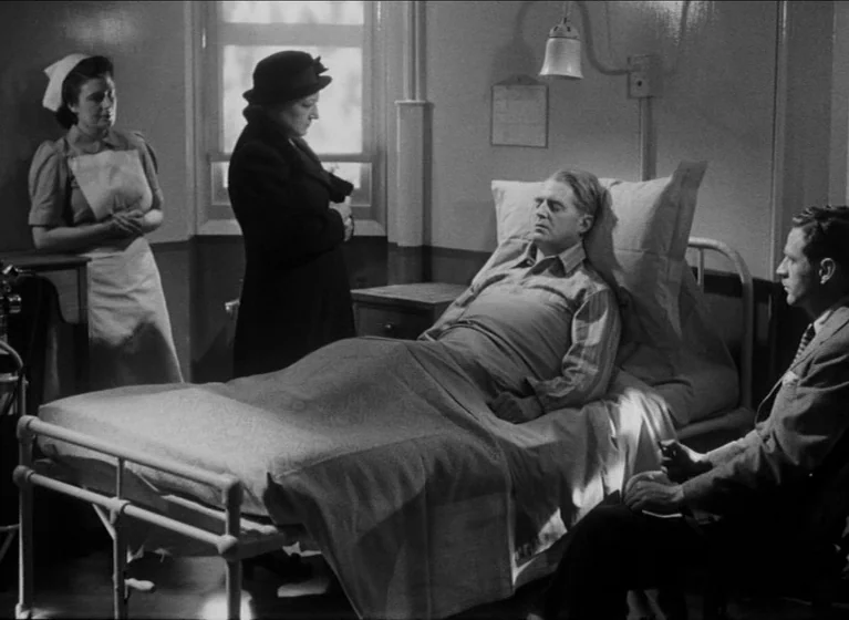 The Blue Lamp (1950) movie still: medium — A hospital room contains a bed with a patient and several visitors. Three people observe a sleeping man…