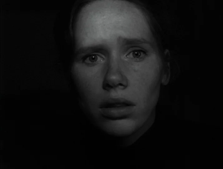 Hour of the Wolf (1968) movie still: closeup — A close-up shot focuses on a young woman emerging from deep shadows. Her face is pale and her…