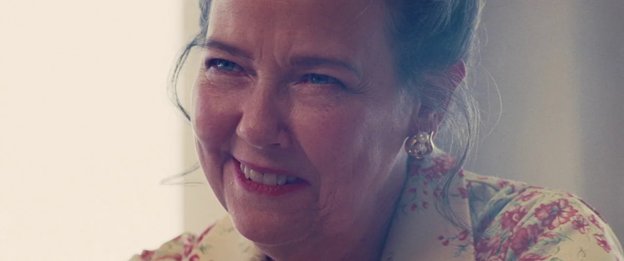 Licorice Pizza (2021) movie still: closeup — An indoor space features soft, diffused light hitting a woman's face from the side. A woman with grey…