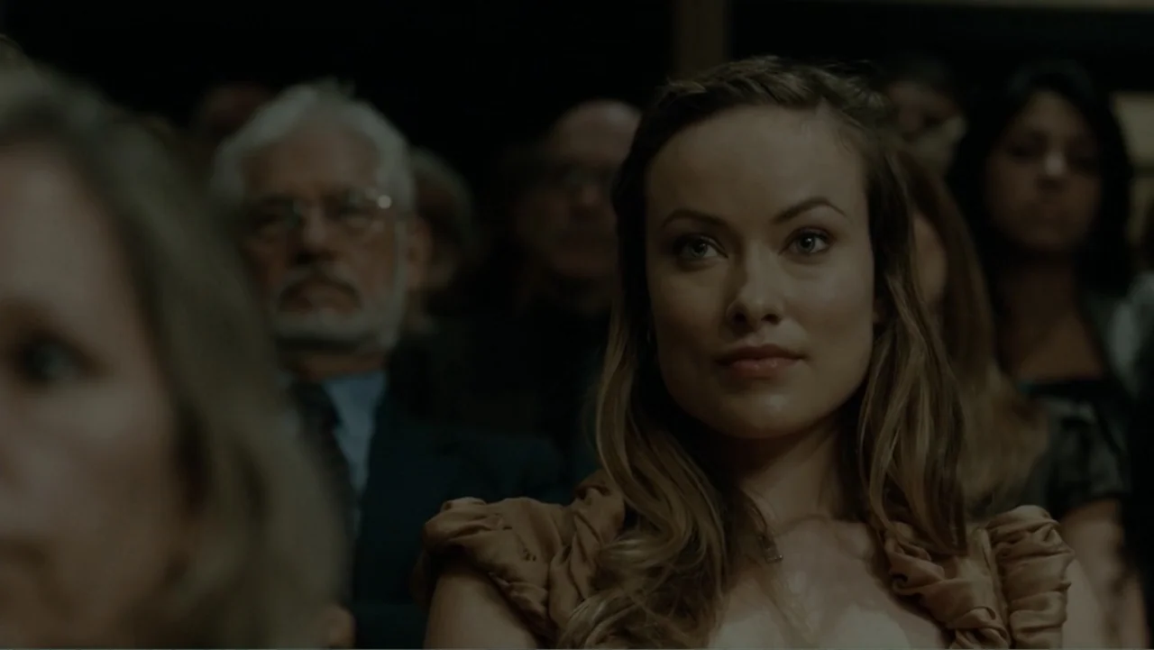 The Words (2012) movie still: medium — An auditorium filled with people sitting in rows while looking toward a focal point. A woman in a tan top…