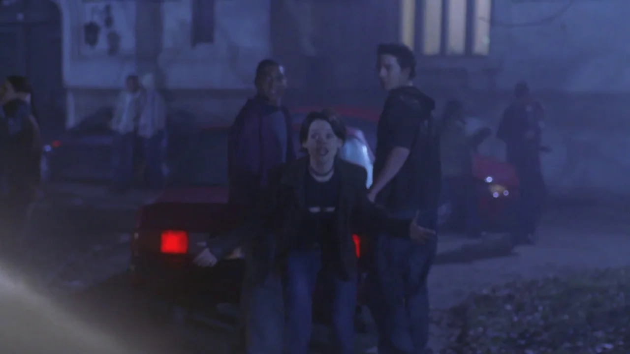 Hellraiser: Hellworld (2005) movie still: medium — A group of teenagers stands near a parked car on a dark suburban road. The street is filled with…