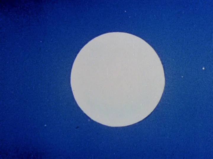 Rabbit’s Moon (1950) movie still: establishing — A bright white circular moon sits centered in a dark, textured deep blue space. The background…