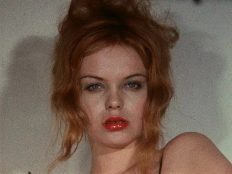 Der Bomberpilot (1970) movie still: closeup — A close portrait shows a woman against a plain, light-colored background. She looks directly forward…