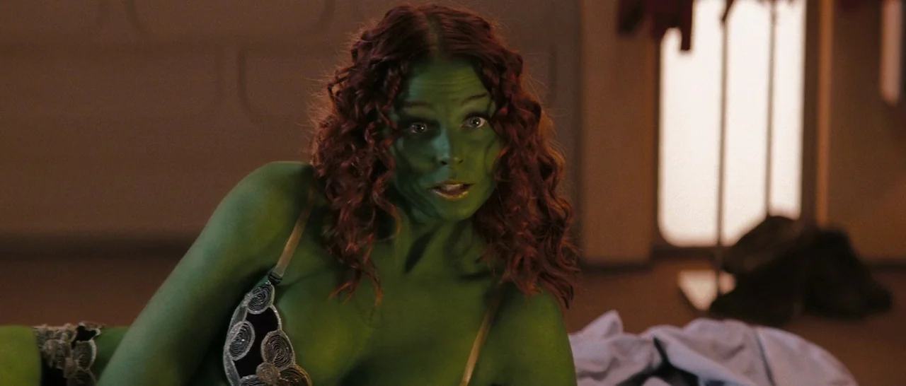 Star Trek (2009) movie still: medium — A dimly lit room provides the backdrop for a green-skinned woman resting on bedding. She leans forward while…