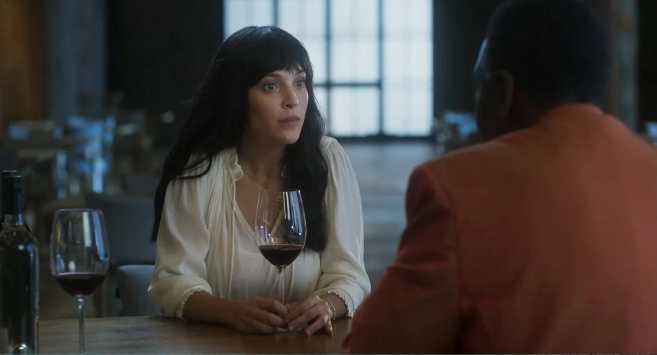 Message in a Bottle (1999) movie still: medium — A restaurant interior with wooden tables and a bright window in the background. A woman in a white…