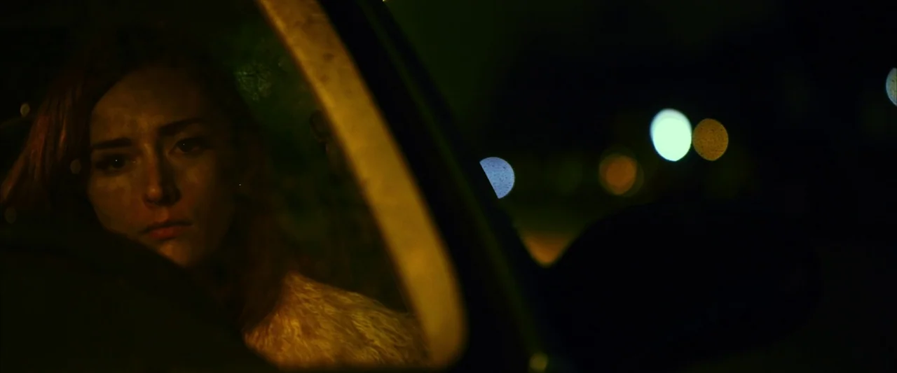 The Stylist (2020) movie still: closeup — A dark vehicle cabin at night with condensation on the glass. A woman sits in the driver's seat looking…