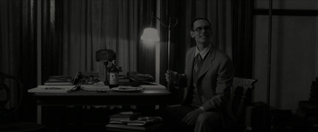 Wonderstruck (2017) movie still: medium — A dimly lit room features a desk with a bottle and scattered papers. A man in a suit sits on a wooden…