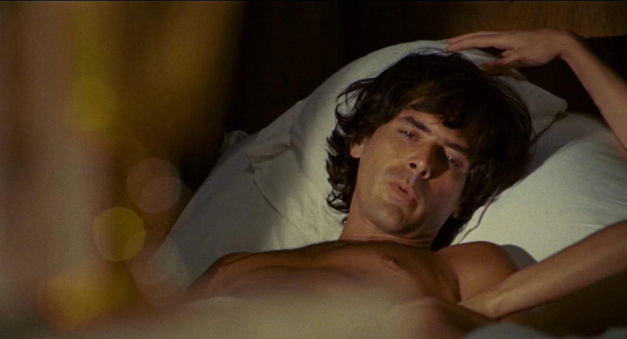 Beatrice Cenci (1969) movie still: closeup — A man lies on a white pillow in a dark room. Another person's hand reaches into the frame to touch his…