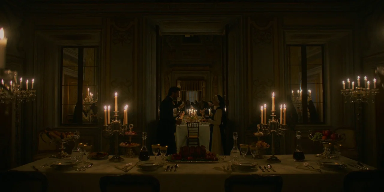 Immaculate (2024) movie still: wide — A dimly lit dining hall features ornate paneling, mirrors, and long tables covered in white linens. A man and…