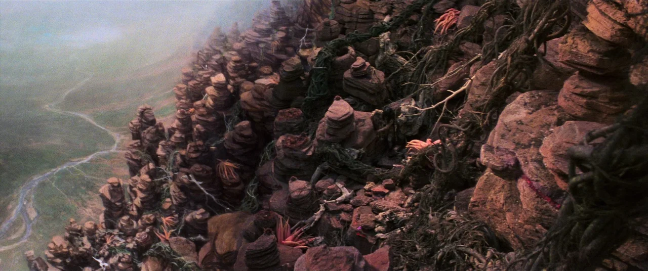 The Dark Crystal (1982) movie still: wide — A rugged cliffside features stacked rock formations covered in thick vines and plant growth. A wide…