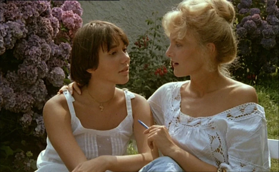 Pauline At the Beach (Pauline à la plage) (1983) movie still: medium — A sunny outdoor space features large, purple hydrangea bushes framing two…