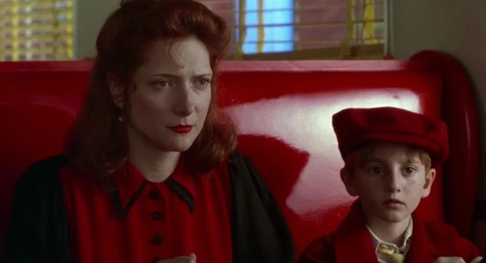 Dick Tracy (1990) movie still: medium — An indoor diner booth features a bright red vinyl bench seat. A red-haired woman and a young boy sit…