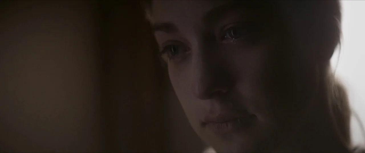 Anything For Jackson (2020) movie still: closeup — A dark indoor space provides a minimal backdrop for a person's close up face. The subject's…