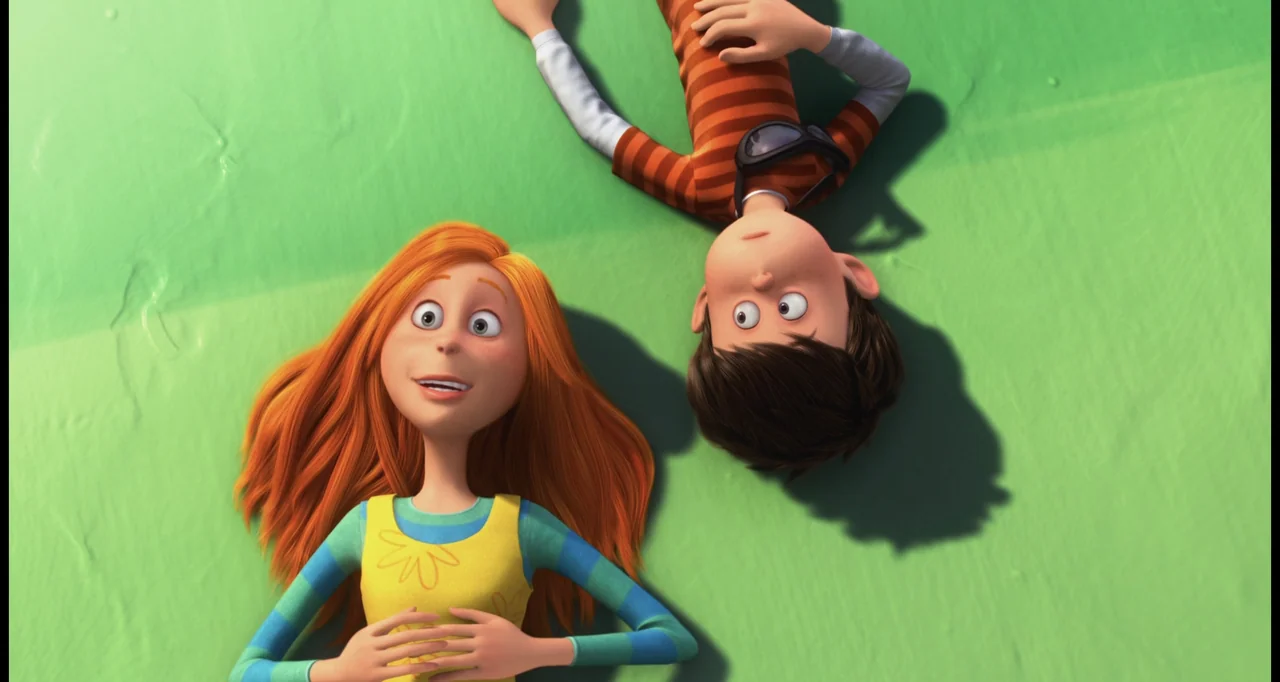 The Lorax (2012) movie still: medium — Two animated teenagers lie side by side on a bright green grassy surface. They are both looking up at the sky…