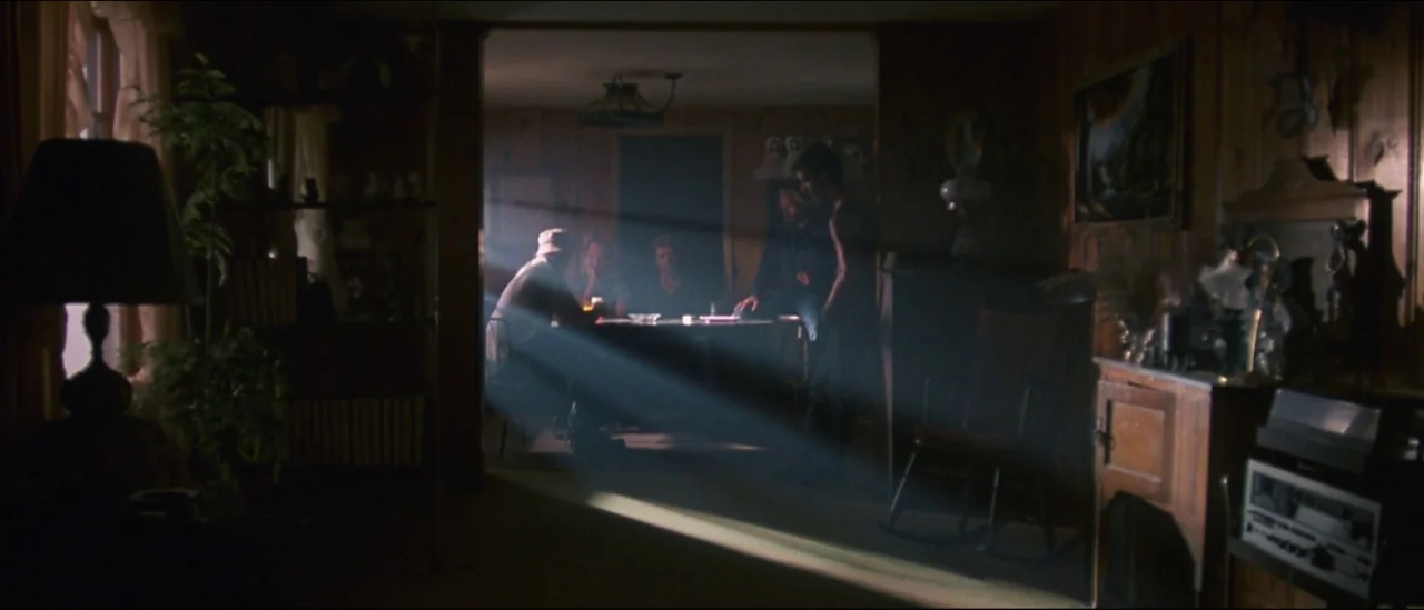 At Close Range (1986) movie still: wide — A dimly lit room with wood-paneled walls features a bright, concentrated shaft of sunlight. Several…