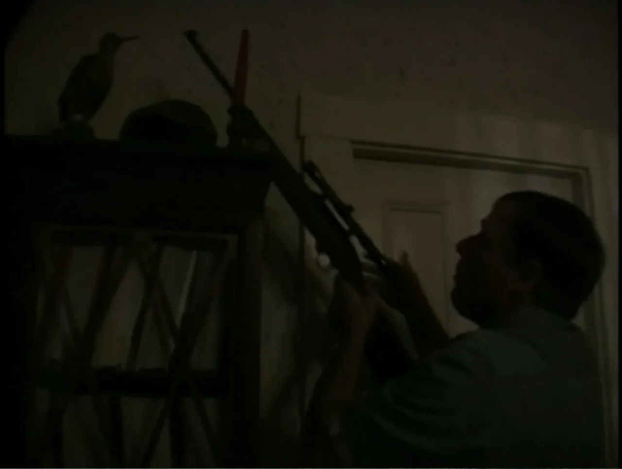 A Rape in a Small Town: The Florence Holway Story (2005) movie still: medium — A dark, dimly lit room contains a wooden shelf holding a decorative…