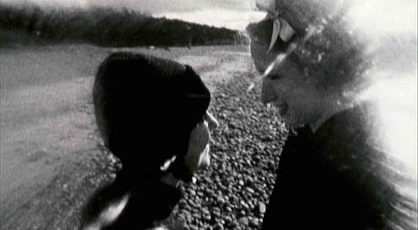 Brand Upon the Brain! (2006) movie still: medium — A rocky beach stretches toward a dark treeline under an overcast sky. Two women face each other…