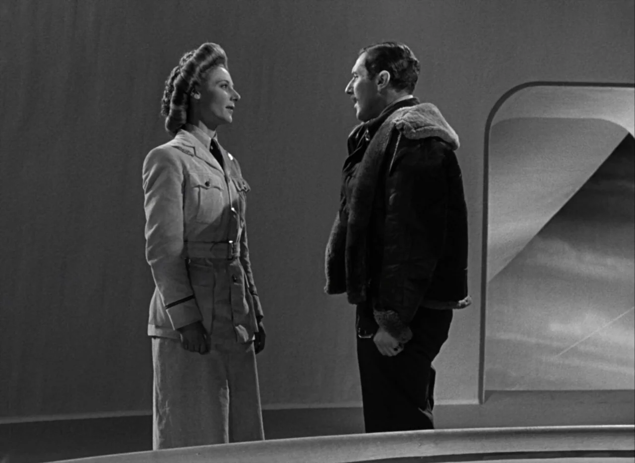 A Matter of Life and Death (1946) movie still: fullbody — A minimalist corridor with curved smooth walls and a recessed arched doorway. A woman in a…