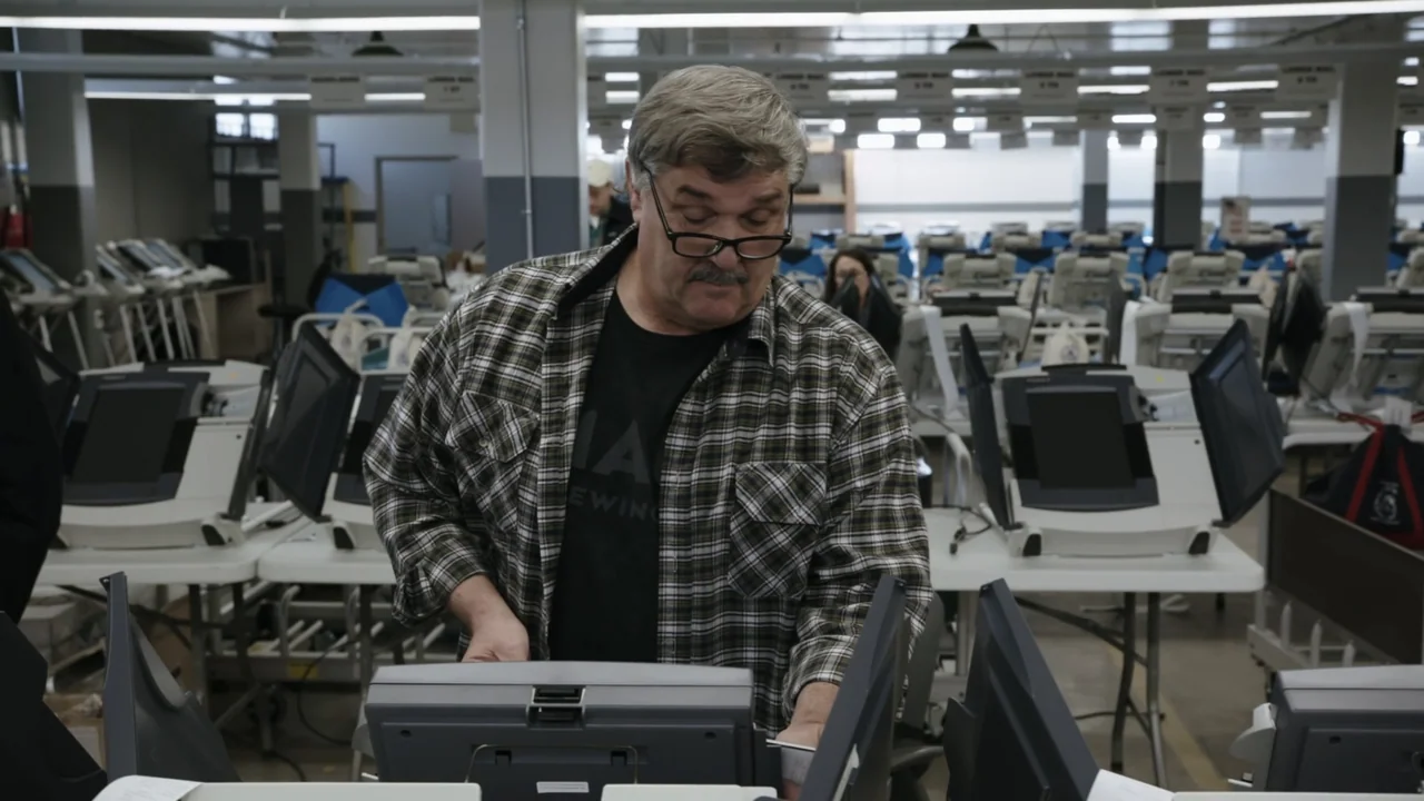Kill Chain: The Cyber War on America's Elections (2020) movie still: medium — A large room configured as a voting center with many electronic ballot…