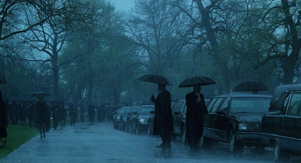 The Weather Man (2005) movie still: wide — A rain-drenched cemetery features a line of parked black hearses and leafless trees. A group of people…