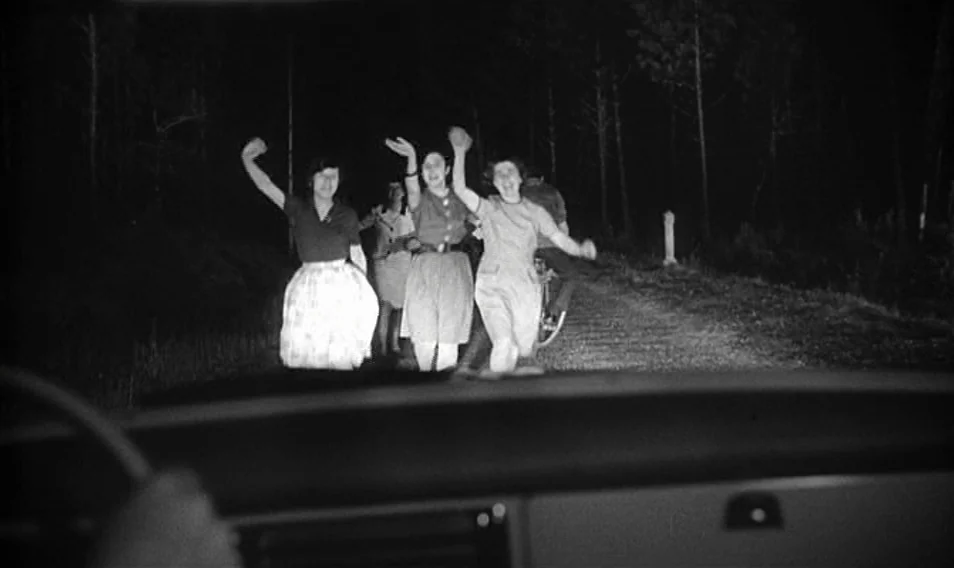 Thérèse Desqueyroux (1962) movie still: medium — Three young women walk toward the camera on a dark country road at night. Their arms are raised…