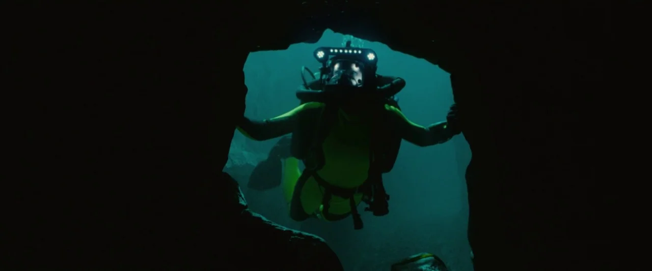 Piranha 3D (2010) movie still: medium — An underwater cavern entrance is illuminated only by the bright headlamps of a scuba diver. The figure swims…