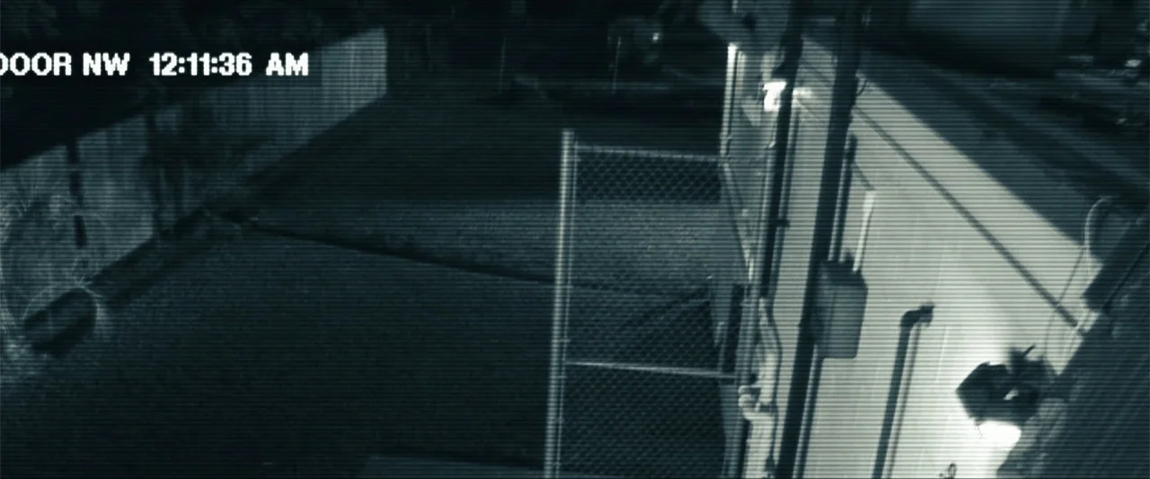 Battleship (2012) movie still: wide — An outdoor area at night is filmed with a high-angle security camera perspective. A chain link fence stands…