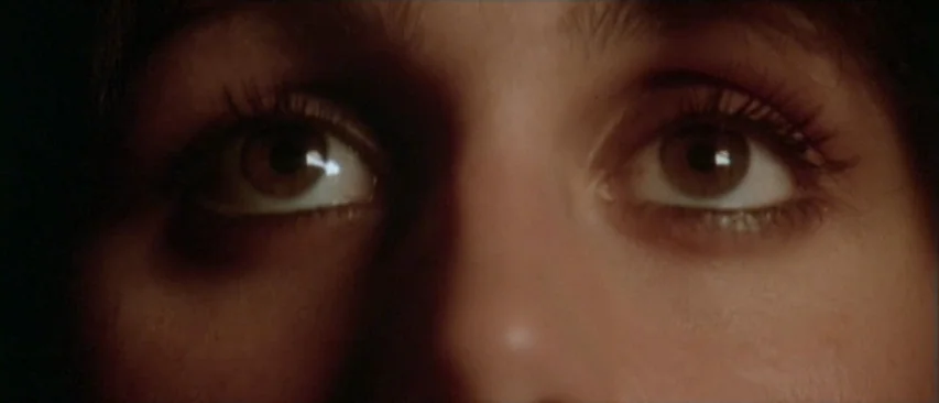 Roadgames (1981) movie still: closeup — A close-up view focuses on a pair of eyes looking upward in darkness. The subject's face is partially…