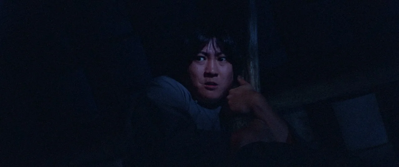 Encounter of the Spooky Kind (1980) movie still: closeup — A dark, dimly lit interior space with a singular vertical wooden support beam visible. A…