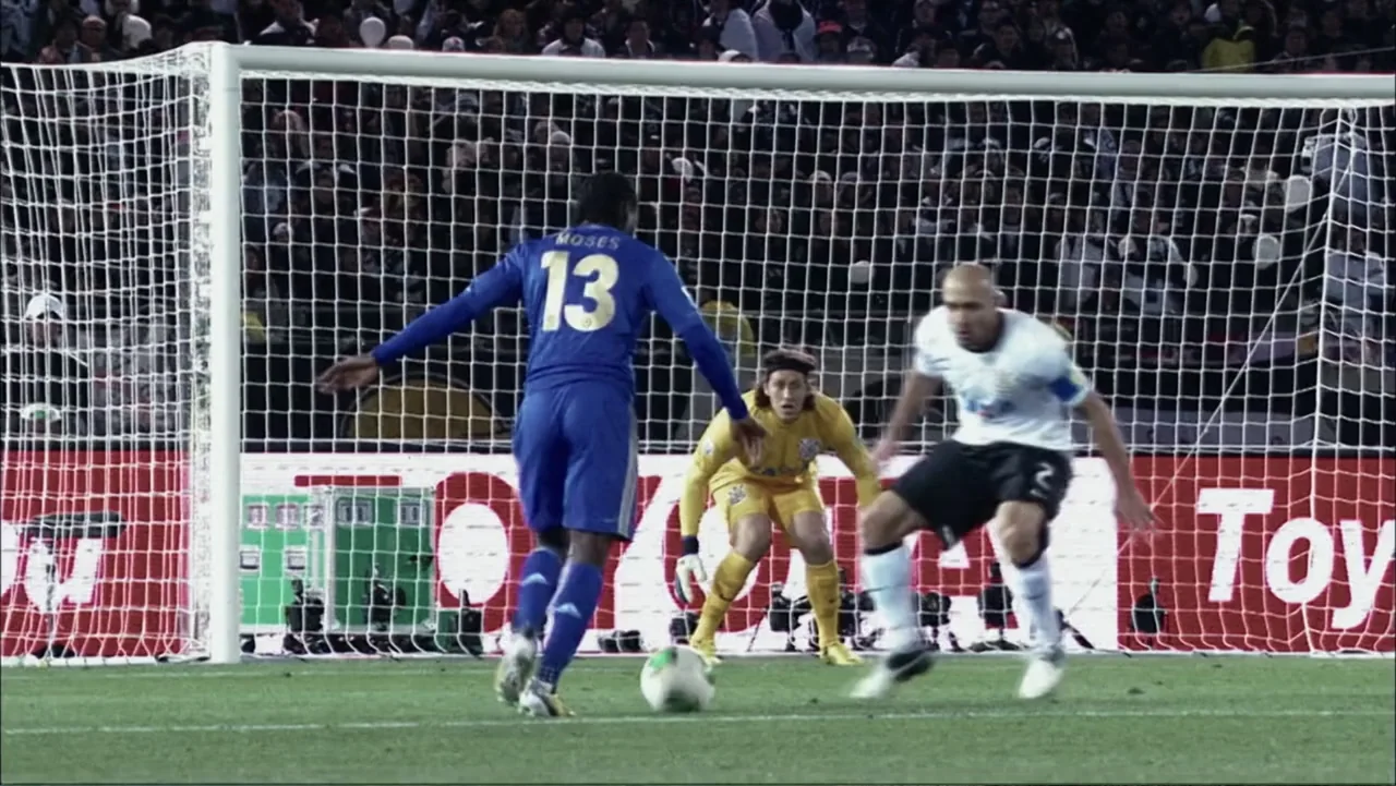 Vai Corinthians (2023) movie still: fullbody — A professional soccer match takes place inside a large stadium at night. A player in a blue jersey…