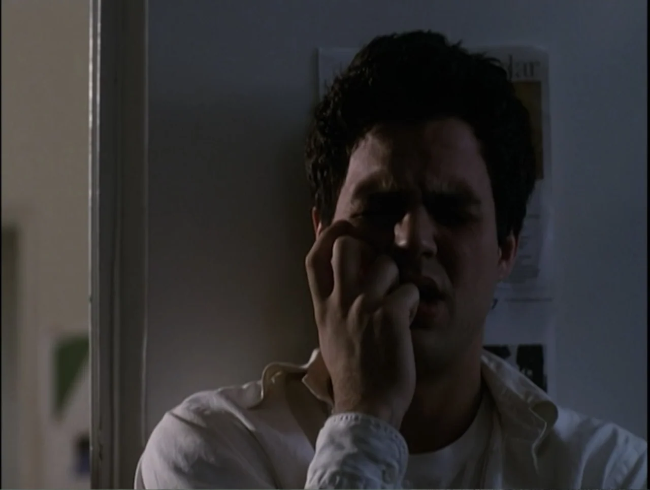 Apartment 12 (2001) movie still: medium — An interior wall area features a person standing next to a doorway. A man presses his hand against his…