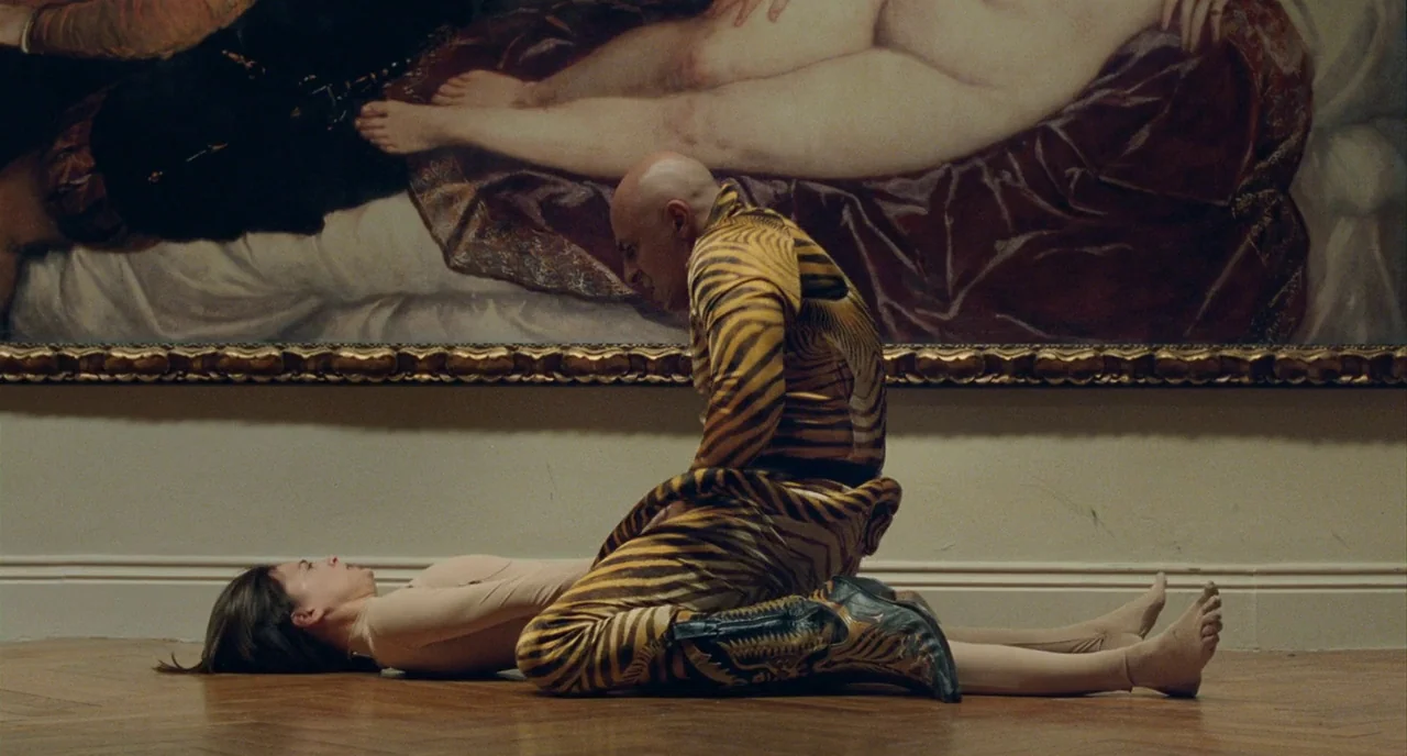 The Skin I Live In (2011) movie still: fullbody — A spacious room features a large painting of a reclining figure on the wall. A man in a…